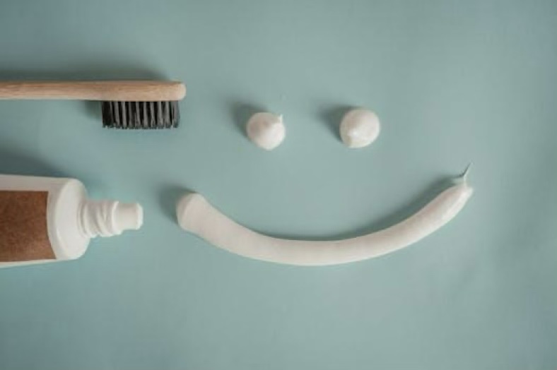 Toothbrush, a tube of toothpaste, and a smile painted with toothpaste