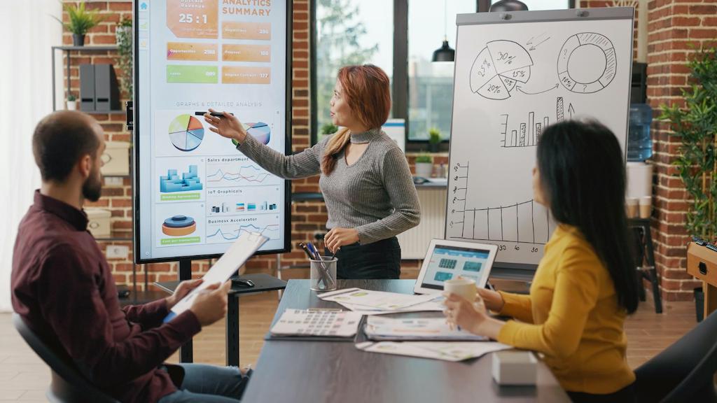 Three people in discussing a marketing strategy plan in a meeting with presentation on display