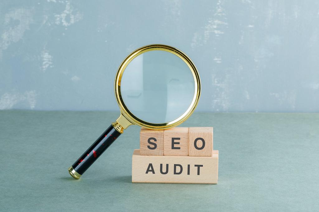 A magnifying glass resting on top of letter blocks spelling SEO Audit