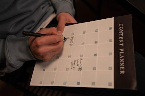 A person writing manually by hand on a content calendar