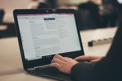 A person typing a structured blog post on a laptop